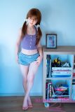 Full-body view of J-cute silicone doll sitting in jeans and purple outfit
